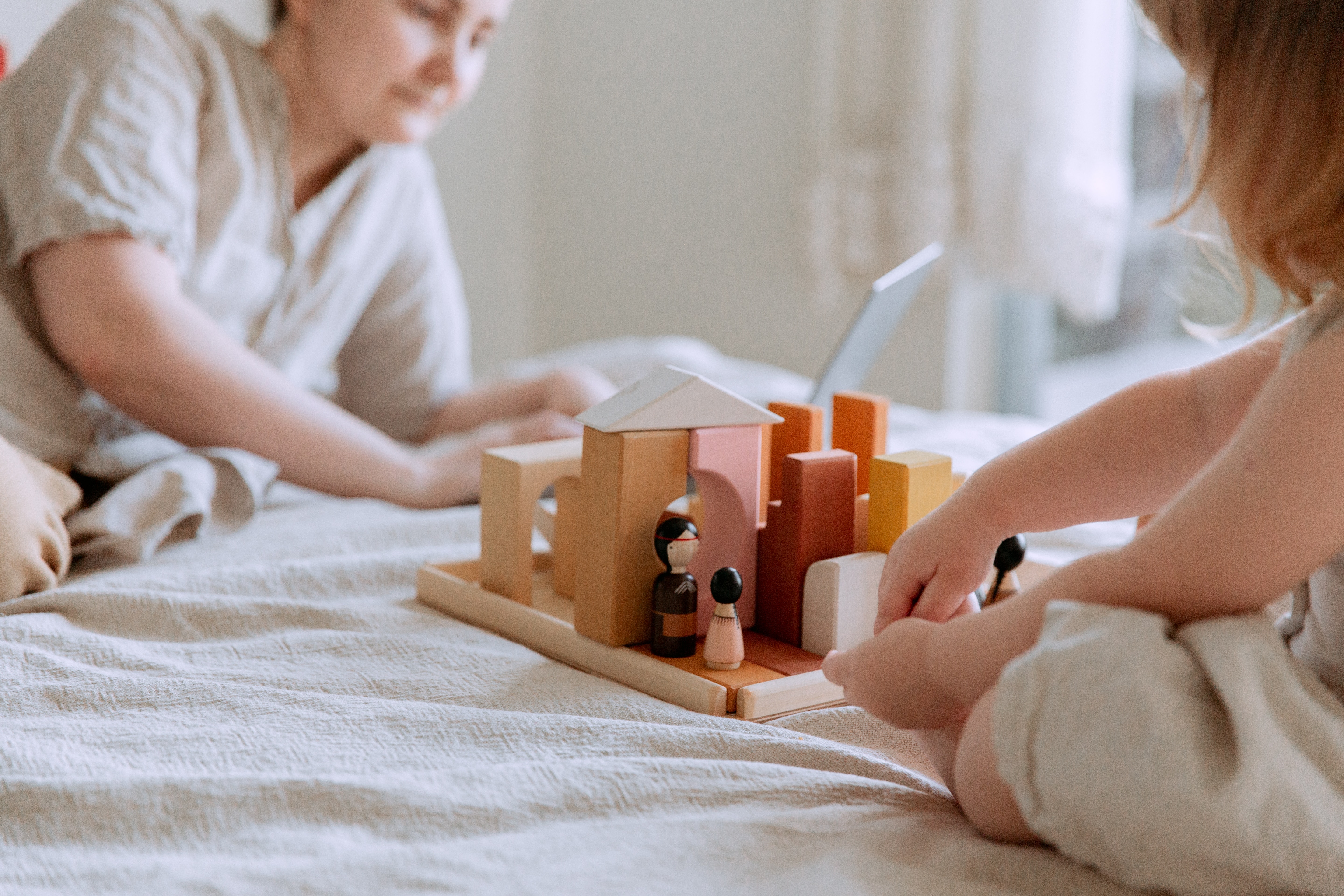 faceless-toddler-girl-sitting-on-bed-and-playing-with-wooden-3975599.jpg