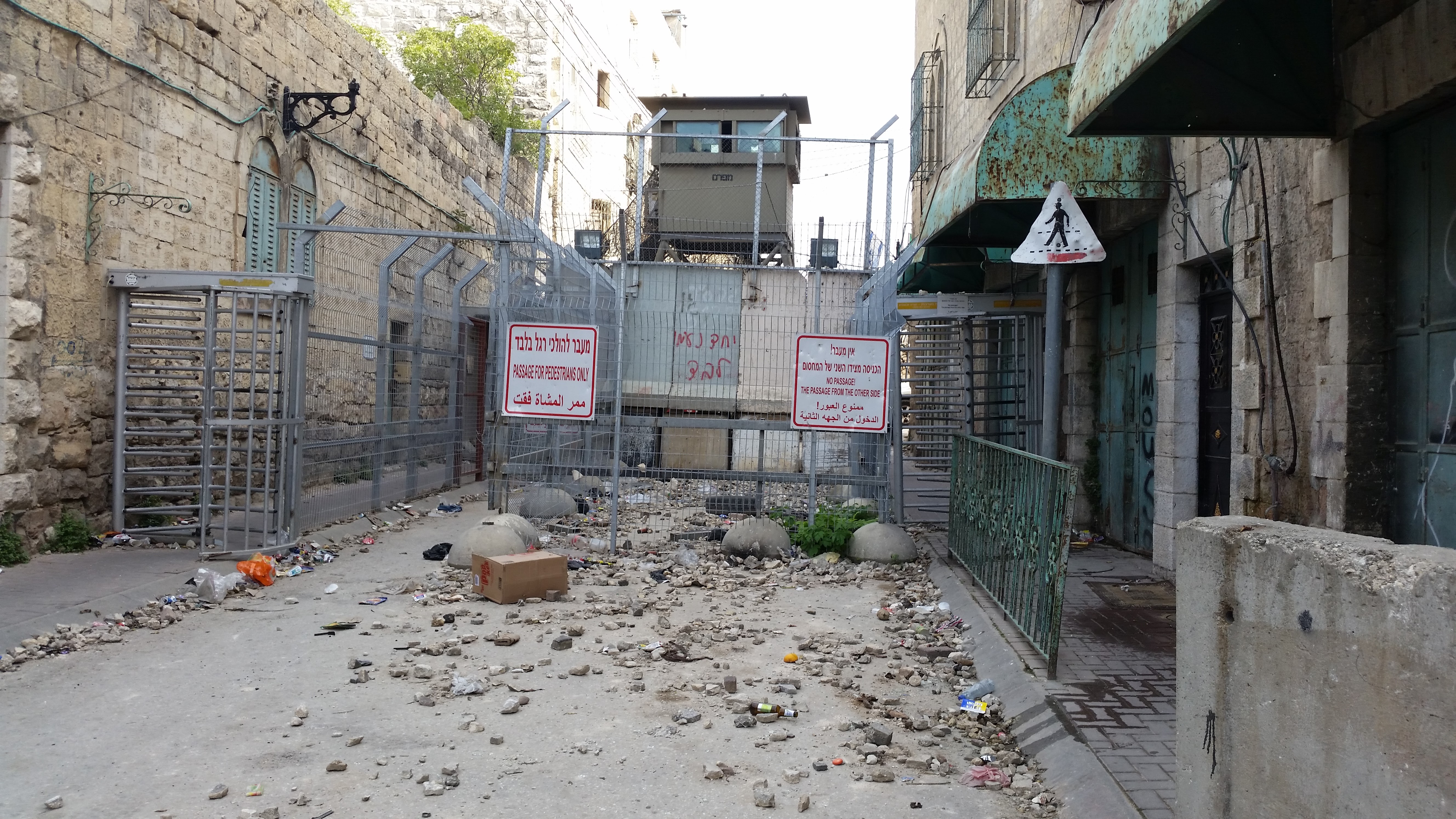 Ellenőrző pont Hebron belvárosában, az Al-Shuhada utcán, az izraeli katonaság lezárta az utcát a palesztin lakosok előtt. Régen ez volt a fő piaci utca, ma már nem lehetnek itt nyitva palesztin boltok.<br />