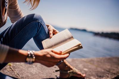 canva_woman_wearing_blue_denim_jeans_holding_book_sitting_on_gray_concrete_at_daytime.jpg