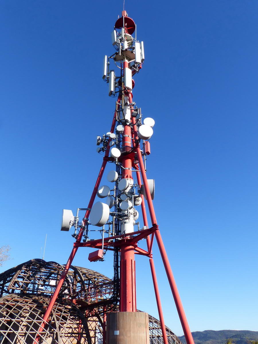 A kilátó mellett áll a csúcson egy magas mobil átjátszó torony is a furán burkolt kiszolgáló épületével