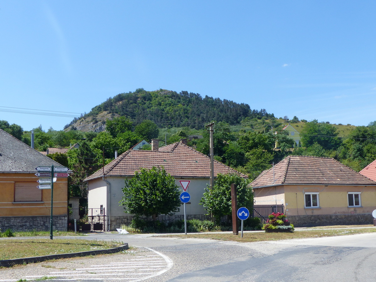 Feltekintés a Hősök teréről a Hegyes-kőre. A csúcs a falu fölé tornyosul.