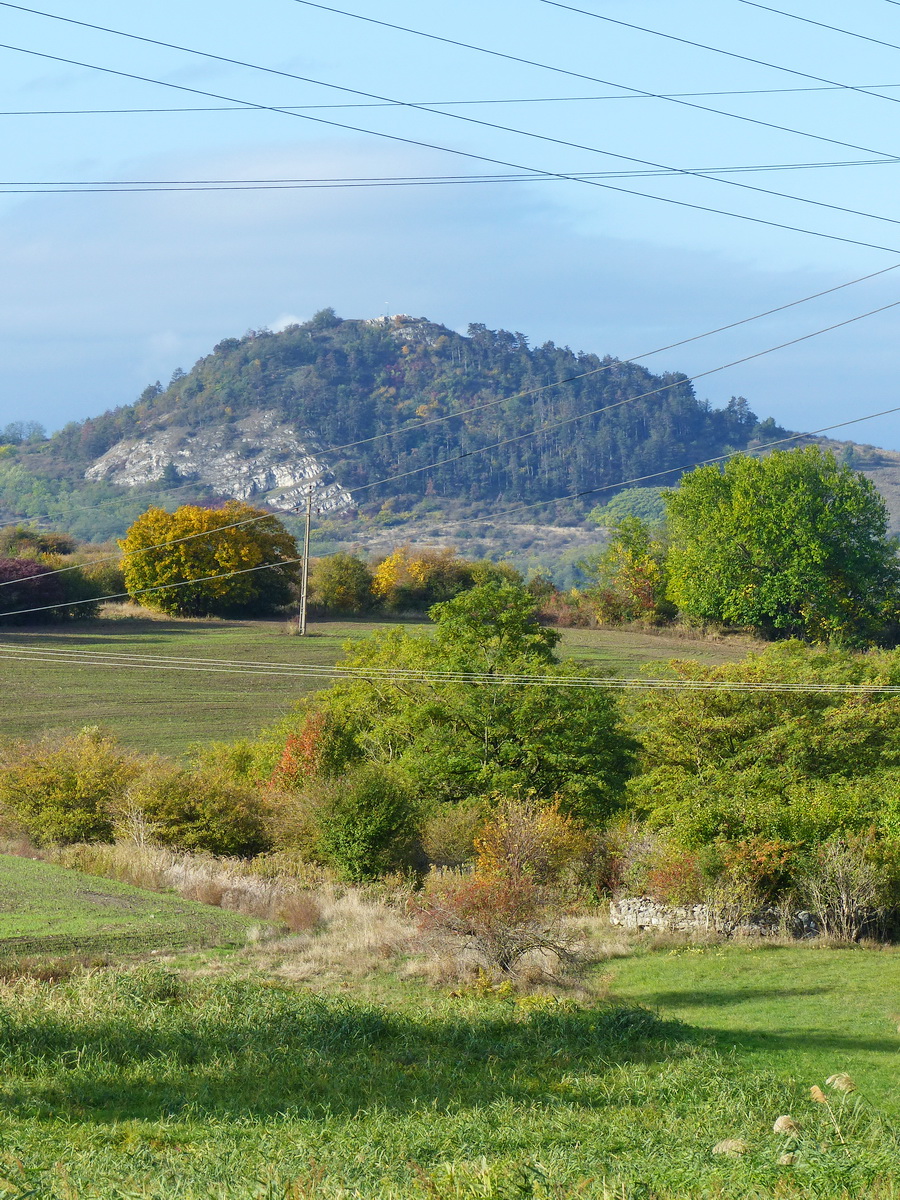 Előtérben a római castrum maradványai, háttérben a távvezetékek pókhálójában a Hegyes-kő áll