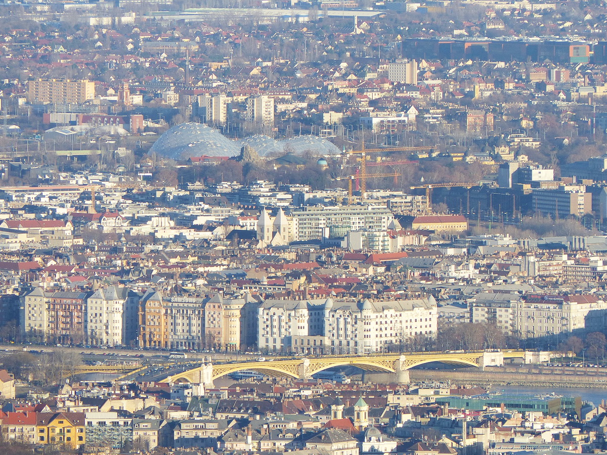 ...alul a Margit híd, felette a Lehel téren álló templom ikertornyai, legfelül pedig az Városligetben épülő Biodóm kupolái látszanak.