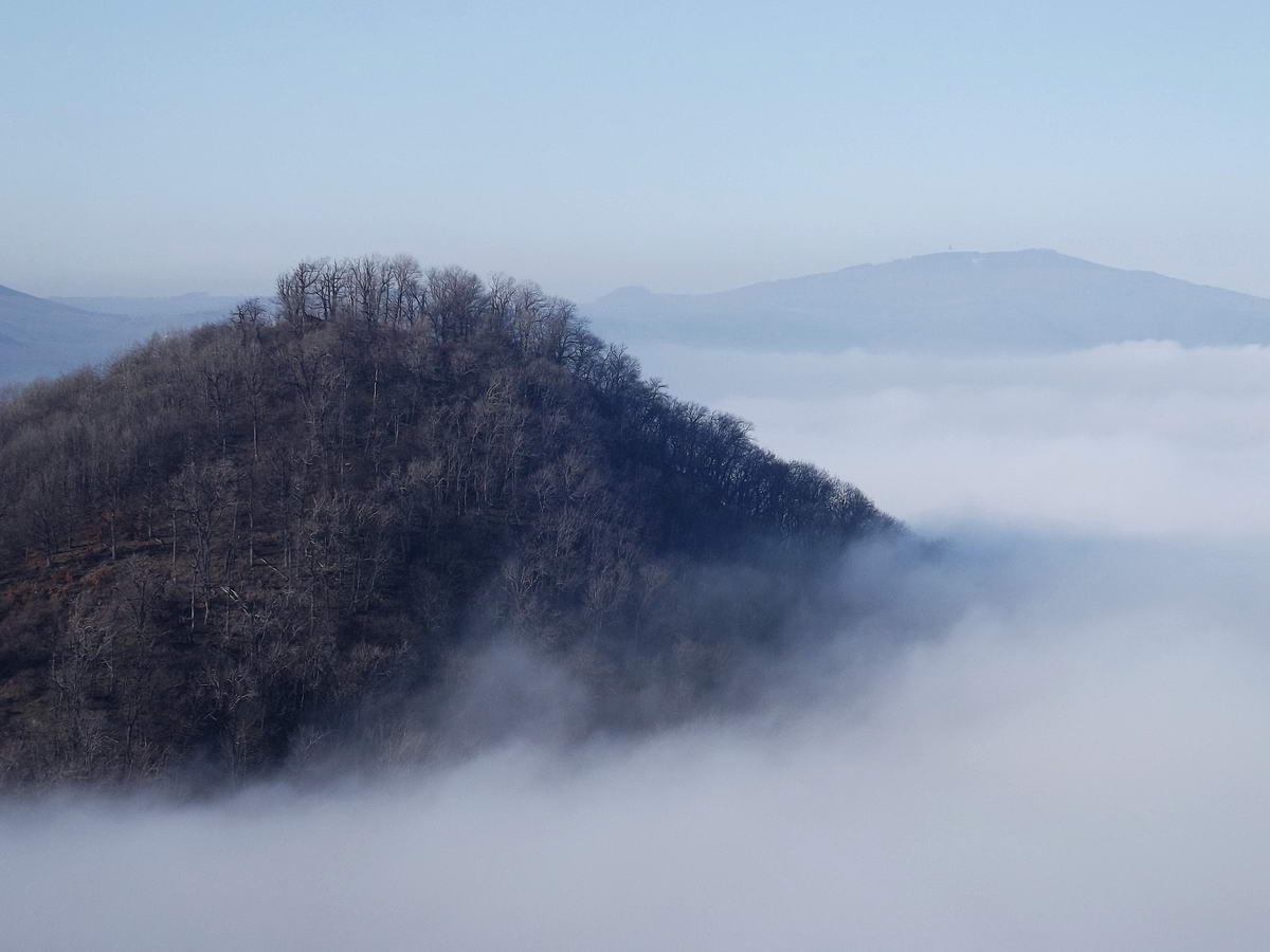 A ködből kiemelkedik az Oroszlánvár csúcsa. A távolban jobbra a Galyatető is látszik.