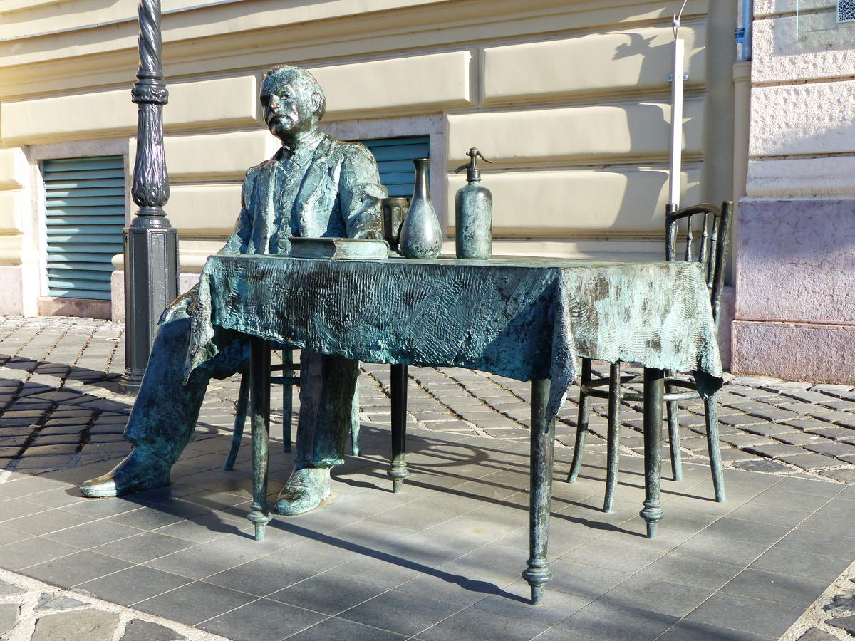 Krúdy Gyula elmerengve ül vendéglői asztalánál