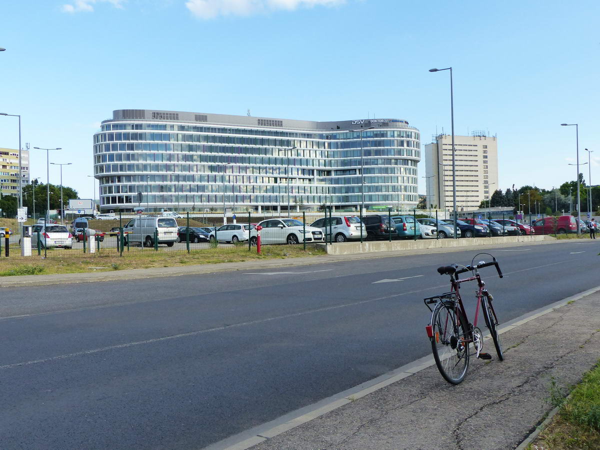 Kelenföldön pózol a kerékpár a vasútállomás P+R parkolói közötti úton. Háttérben a lassan már teljesen elkészülő Budapest One irodaház áll