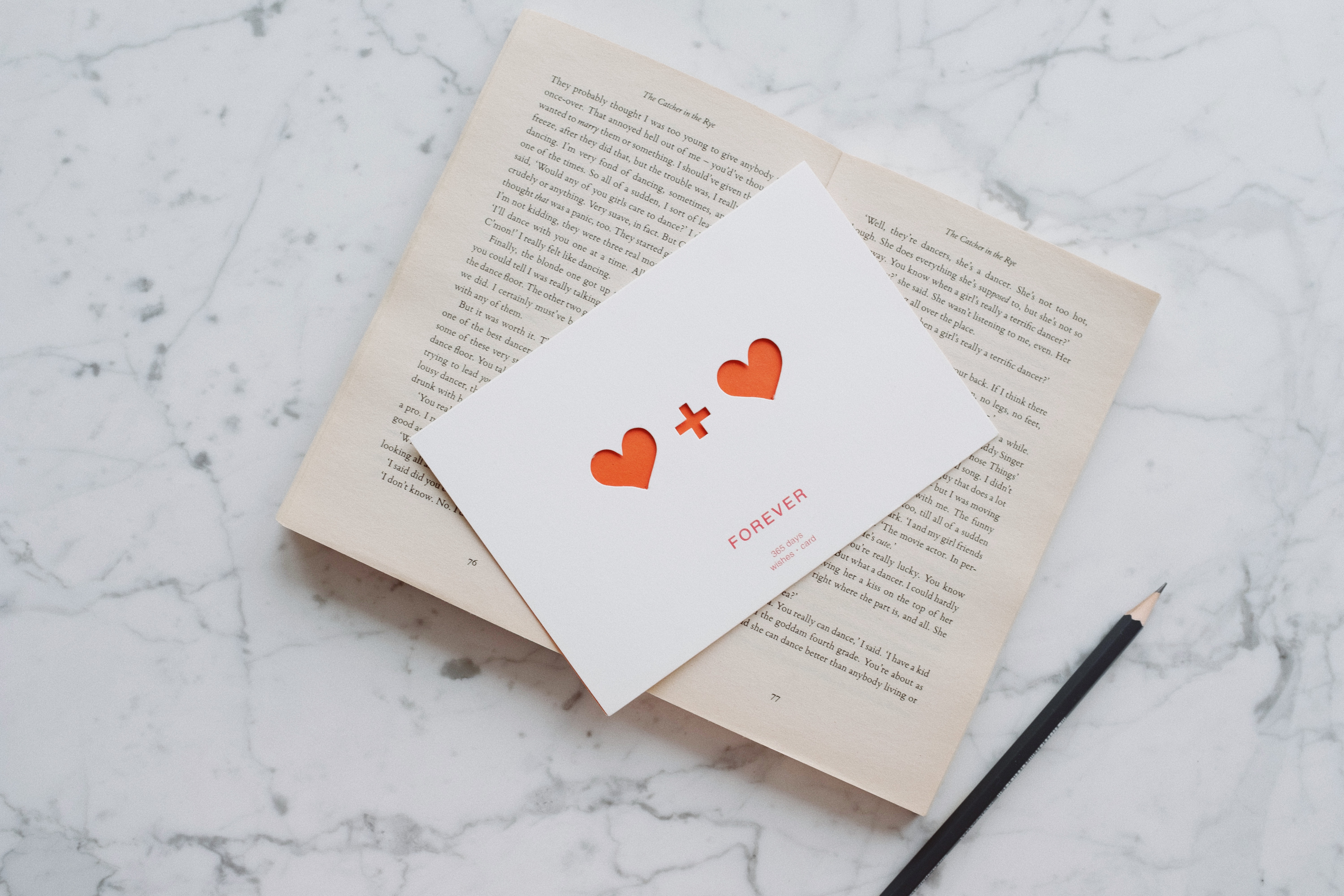 opened-book-with-pencil-and-romantic-postcard-on-marble-3847636.jpg