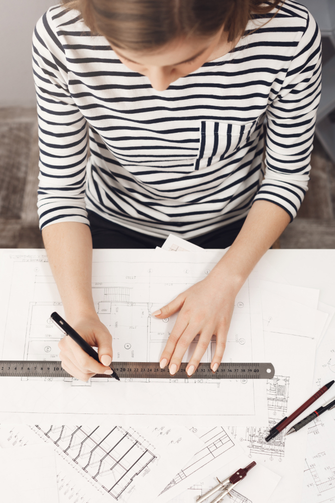 close-up-view-from-top-concentrated-young-good-looking-female-architect-making-her-new-project-apartments-using-ruler-pen.jpg