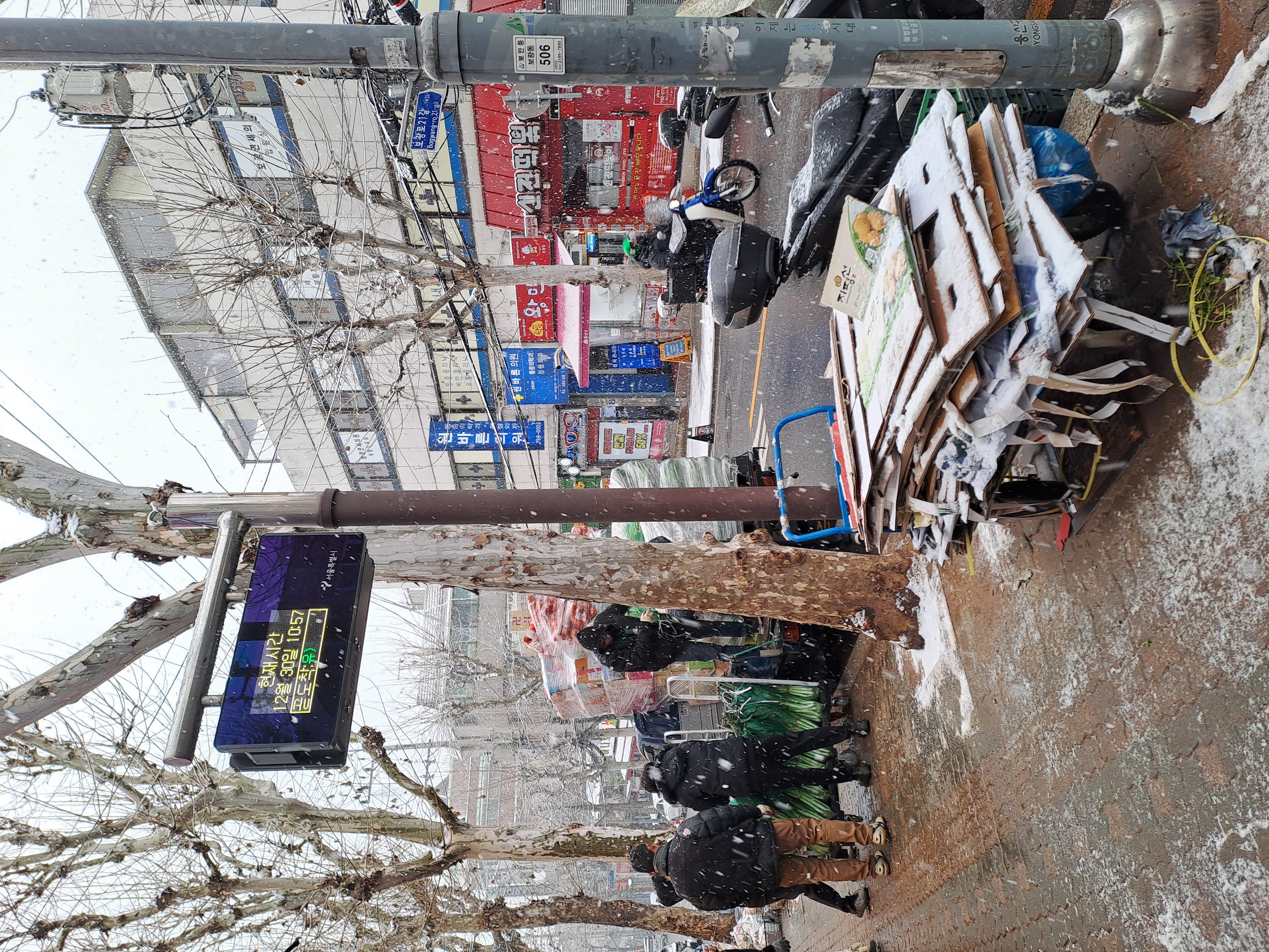 A munka ilyenkor sem állhat meg: a boltosok bevásárlókocsikkal szánkózva pakolták le a friss zöldséget a szakadó hóban.