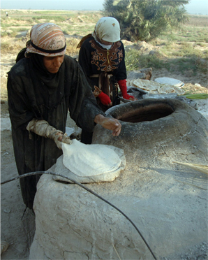 an_iraqi_woman_making_flat_bread_in_a_tabun_style_oven.jpg