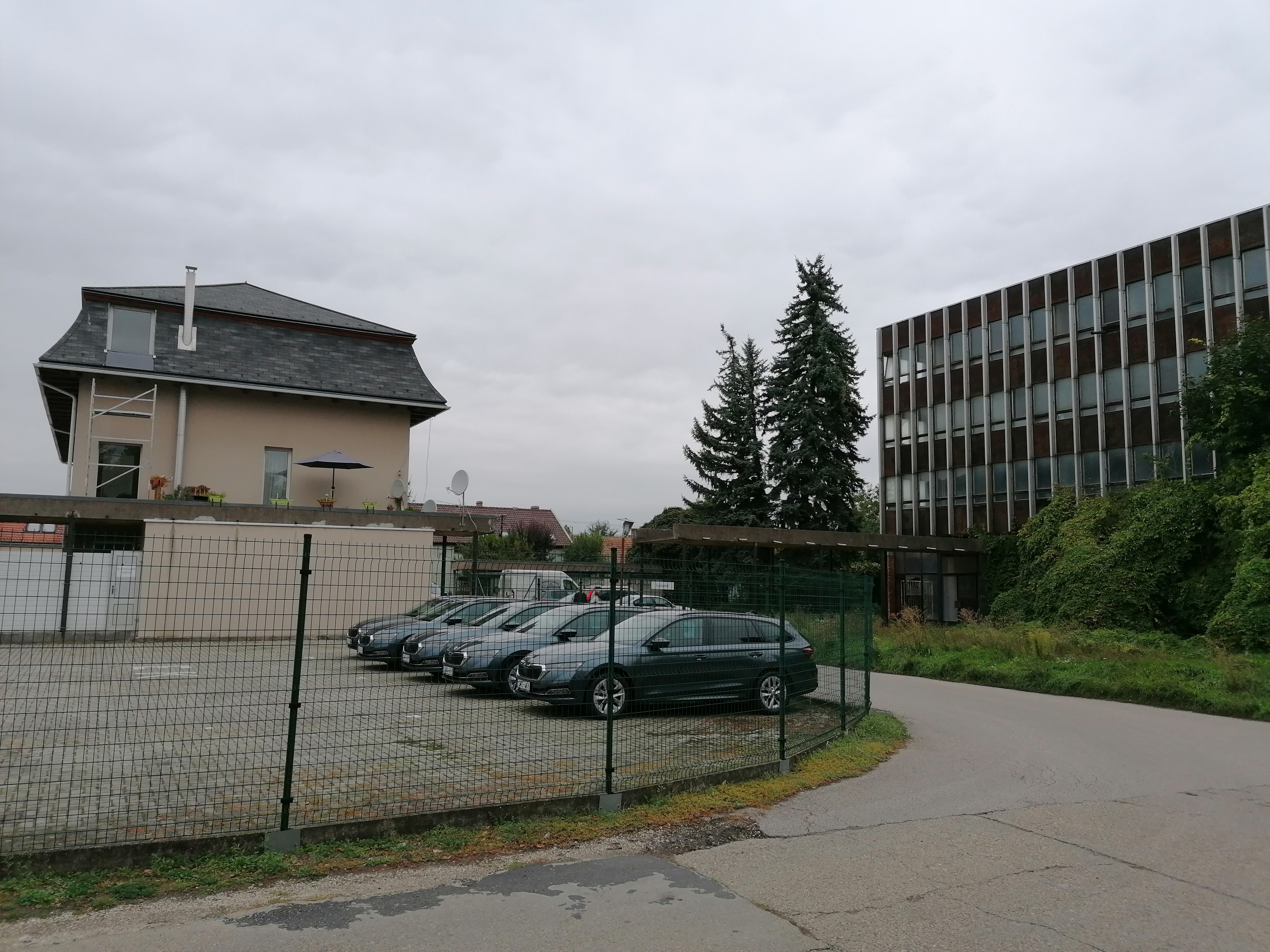 Az épületegyüttes az egykori gyárterület felől, jobbra az irodatömb, balra az egyik átépített öltözőépület. A kettőt összekötő, nyitott árkád kivehető. Fotó: KD, 2021.09.29.