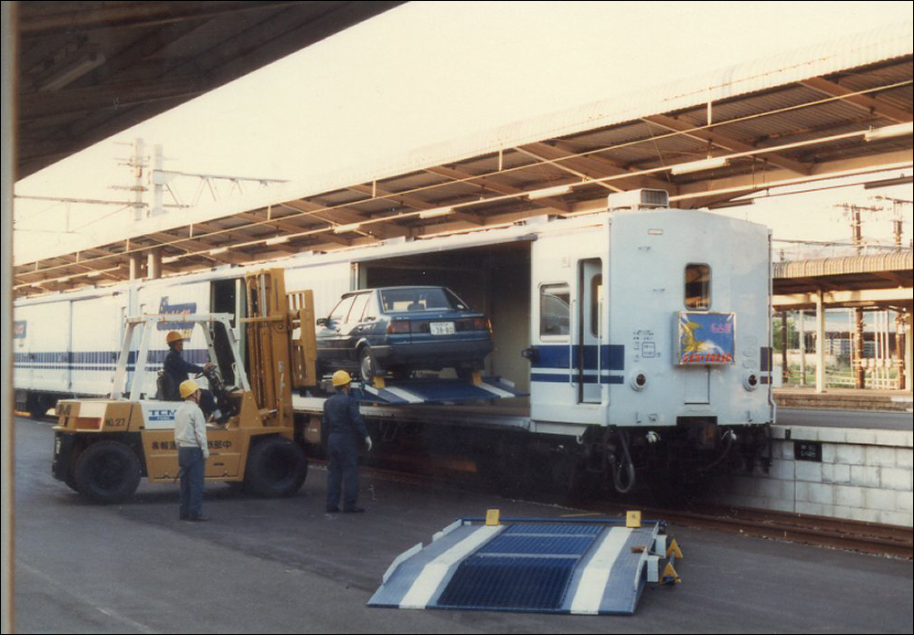 Autók berakodása a „Euroliner” (ld. később) festésű, a nagoya-i Atsuta és Higashi-Kokura között közlekedő „Car Train Euro Nagoya” egyik MaNi 44-es sorozatú kocsijába. (Fotó: Sakurai Kenichi)