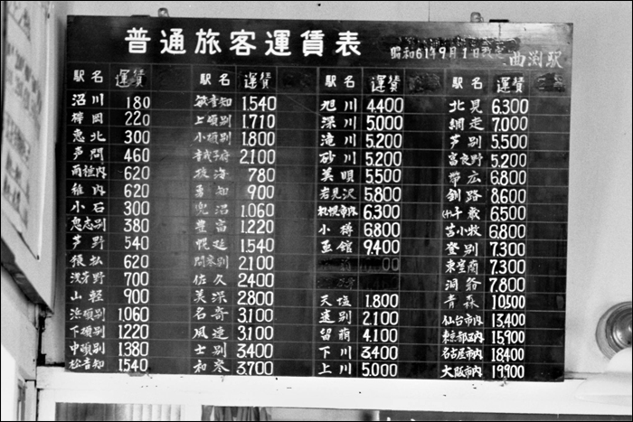 Díjszabási táblázat Magarifuchi állomáson 1986 decemberében, 2 és fél évvel a vonal bezárása előtt. Wakkanai innen 620 (34,9km), Sapporo pedig 6300 yenbe (383,6km) került, de olyan „egzotikus” helyeket is megtalálhatunk, mint Aomori (10500 yen), Tokyo (15900 yen), Nagoya (18400 yen) vagy éppen Osaka (19900 yen). (Fotó: Komura Makoto)