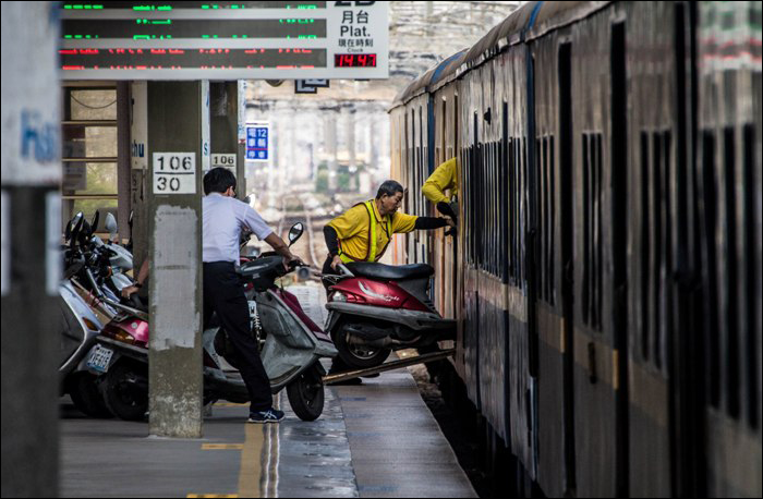 A TRA munkatársai pakolják vonatra az utasok által feladott robogókat Hsinchu állomáson.