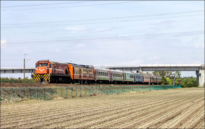 TRA R100-as sorozatú (EMD G22U) dízelmozdony halad kirándulóvonatával Kanding (崁頂) állomás közelében.