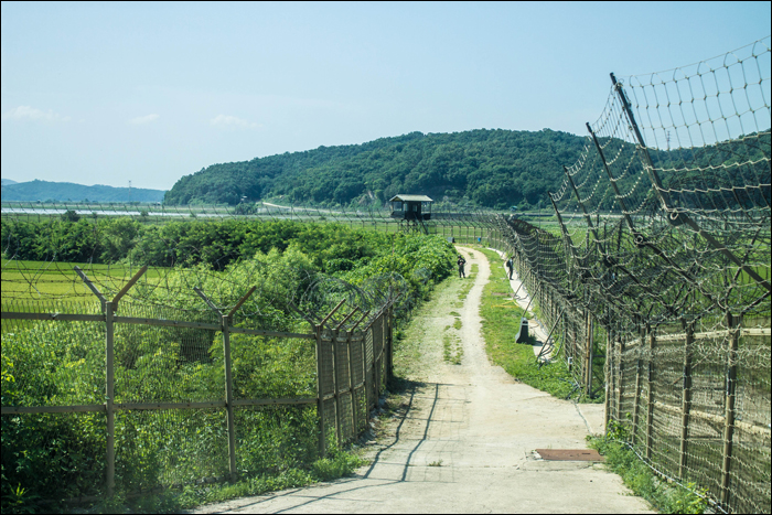 Békésen fűkaszáló katonák a Dél-Korea (bal) és a demilitarizált zóna (jobb) között húzódó határvonal mentén. A tényleges, észak-déli határ innen még jó néhány kilométerre található.