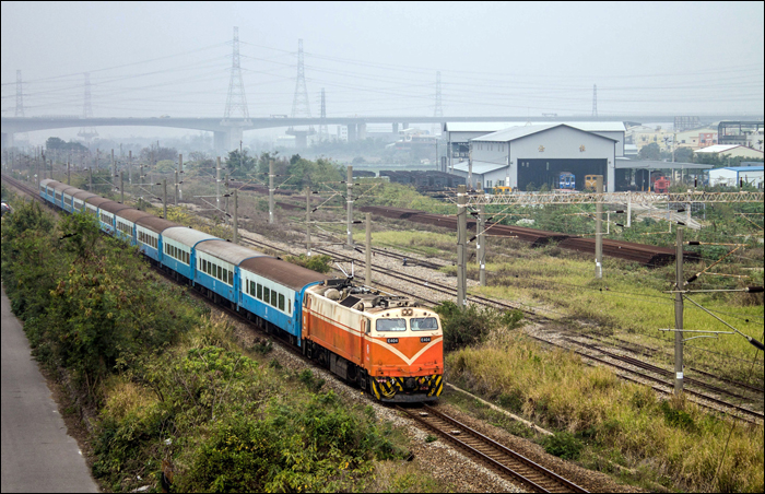 GE E42C típusú TRA E400-as sorozatú villamos mozdony halad Qidu (七堵, qīdǔ) – Changhua (彰化) viszonylatú „Fu-xing Semi-Express” (復興號, fùxīng hào) vonatával Dadu (大肚, dàdù) közelében.