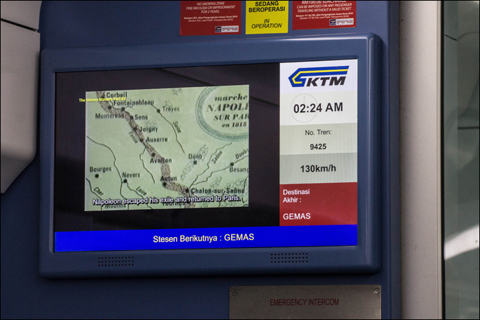 Információs kijelző a KTMB Class 93 fedélzetén, melyen az alapvető utazási információkon felül dokumentumfilmeket is élvezhetnek az utasok.