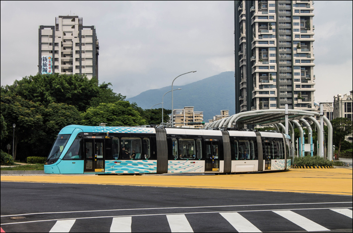 A Danhai LRT egyik járműve halad a „nevezetes” Binhai Rd. – Shalun Rd. kereszteződésben, melyből „kimaradt” a felsővezeték, melyen a villamosok a képen is látható módon, leengedett áramszedővel, akkumulátor segítségével jutnak át.