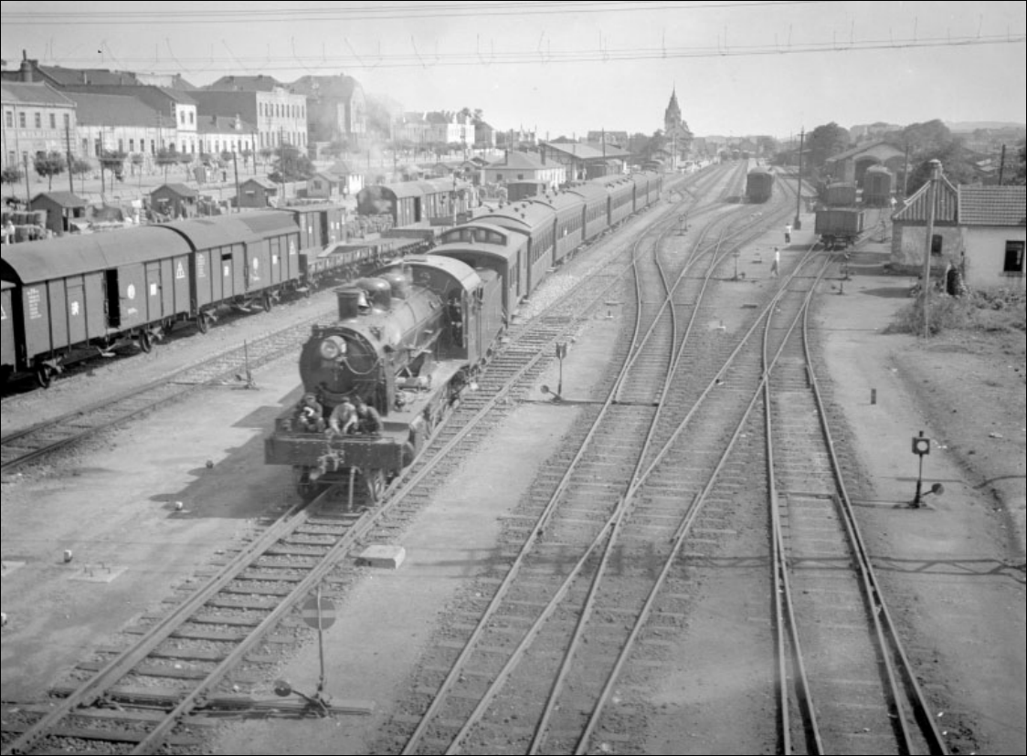 A Berliner Maschinenbau AG egyik 4-6-0 tengelyelrendezésű mozdonya indul vonatával Qingdao állomásról. A mozdony a Shandong Vasúttársaság idején 300-as sorozat néven volt ismert, mely a japán fennhatóság alatt TeHoShi-ra változott. A mindössze 5 példányban készült jármű később TH4 néven vonult be a Kínai Népköztársaság vasúti történelmébe. (Fotó: Ulrich Fuhrmeister)