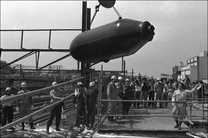 A Japán Önvédelmi Erők tűzszerészei és néhány újságíró figyelik a Tohoku shinkansen építése során talált 1 tonnás bomba eltávolítását, melynek hatástalanításán közel egy órán át dolgoztak a szakemberek. A minden bizonnyal az USA hadserege által hátrahagyott bomba hatástalanításának idejére a JNR 6, közelben húzódó vonalán szünetelt a forgalom, illetve 500 méteres körzetben mindenkit evakuáltak. (Forrás: Asahi)