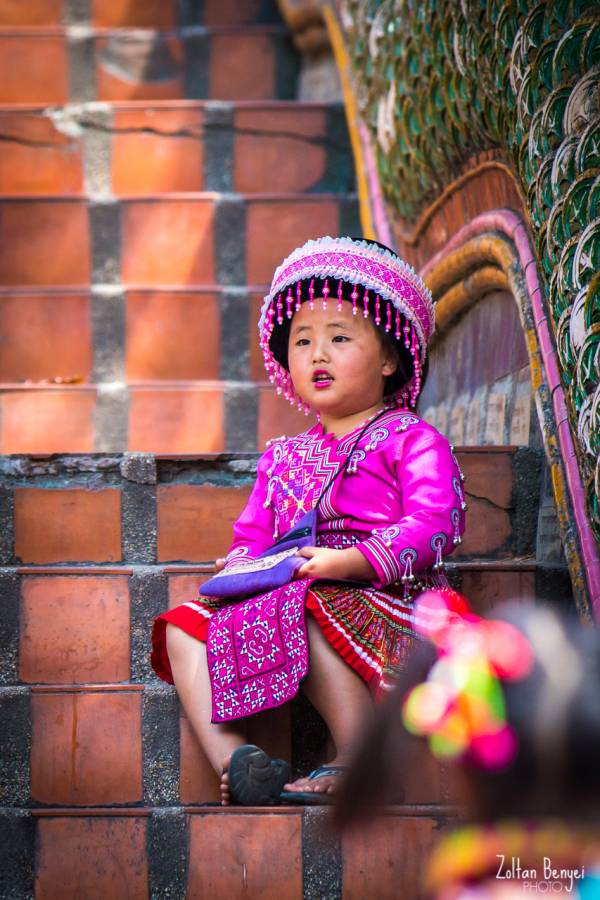 Hely népviseletben ülő thai kislány a Wat Phrathat Doi Suthep lépcsősorán