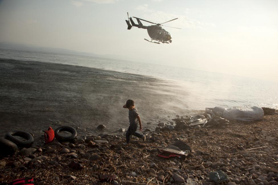 Egy szíriai gyerek fordítja el a fejét, miközben az EU-s határvédelmi szervezet, a Frontex helikoptere járőrözik a görög Leszbosz szigetének partjainál. (f.: Reuters)