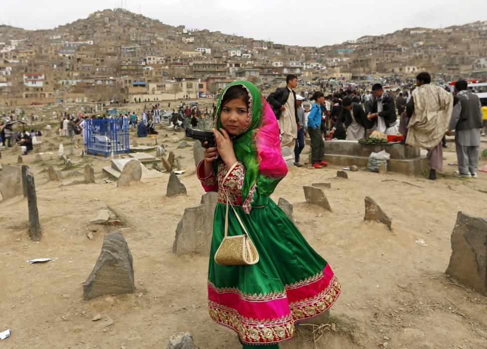 Díszruhába öltöztetett fiatal lány játszik játékpisztollyal a perzsa újév ünneplésére összegyűlt tömegben, az iraki Kabulban (f.: Reuters)