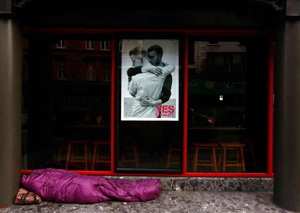 Egy hajléktalan alszik a földön az ‘Igen, egyenlőség‘ feliratú, a melegházasságot támogató választási plakát alatt. Írországban péntek reggel kezdődtek meg a melegek házassági jogainak engedélyezéséről szóló népszavazások, amelyeken előzetes információk szerint az igenek fognak többségbe kerülni - még a kormányfő is emellett kampányolt. (f.: Reuters)