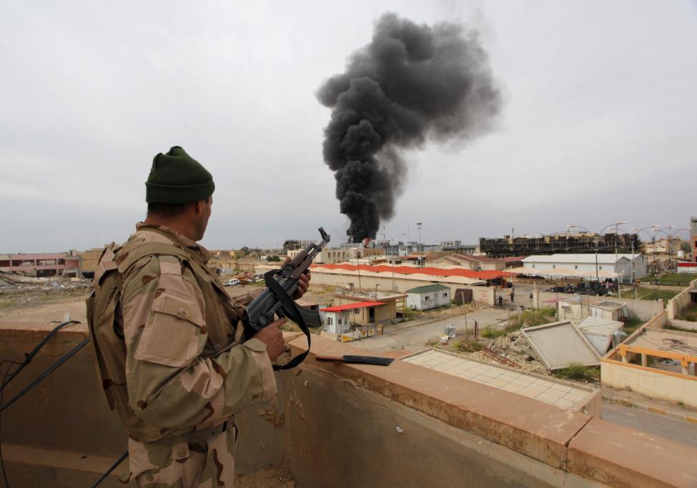 Az iraki hadsereg egyik katonája figyeli a Tikrit városából felszálló füstöt, miközben próbálják kiűzni az Iszlám Állam fegyvereseit a térségből (f.: Reuters)