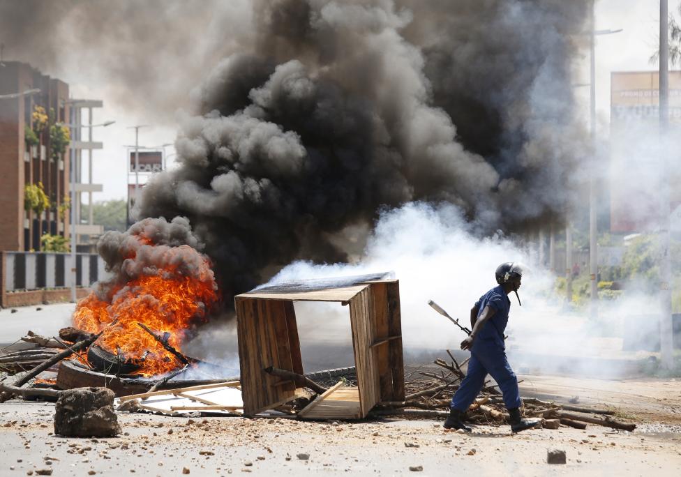 Egy rendőr halad el a Burundiban felállított számtalan lángoló barikád előtt. A héten az elnök távollétében Godefroid Niyombare tábornok a hadsereg több tagjával együtt puccsot kísérelt meg, azonban végül ez sikertelen volt, a hatalom továbbra is Nkurunziza kezében van. (f.: Reuters)