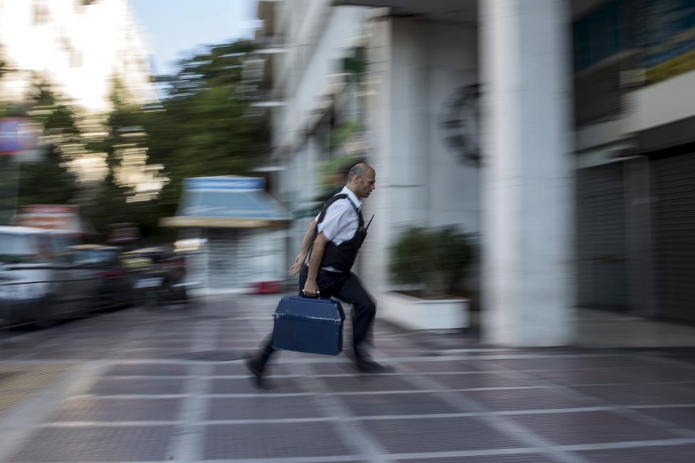 Banki biztonsági őr szállít készpénzt az egyik bankfiókba Athénban. A héten Görögország gyakorlatilag csődbe ment, mikor június 30-án nem tudta visszafizetni az IMF-nek járó hiteltartozásait. Ciprasz miniszterelnök és az eurózóna államai tovább folytatják a tárgyalást az ország jövőjével kapcsolatban. (f.: Reuters)