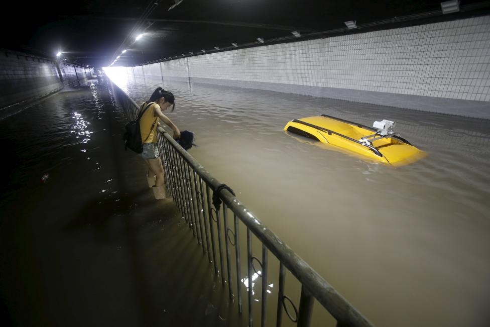 Kínai nő próbál átjutni a heves esőzések során víz alá került alagúton. (f.: Reuters) 