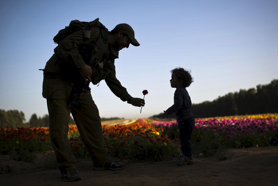 Egy izraeli katona nyújt át egy szál virágot egy gyereknek a Gáza-övezetben lévő  Nir Yitzhaknál. (f.: Reuters)