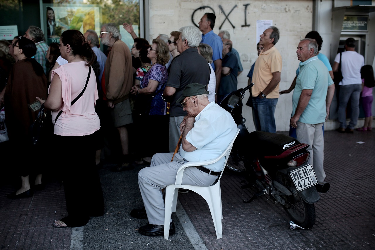 Nyugdíjas férfi ül egy bankfiók előtt, amelyet tüntetők rohamoztak meg Görögországban. A falon látható ‘oxi‘ (jelentése: nem) felirat a vasárnap tartandó népszavazásra utal, ahol a nemleges szavazat az EU megszorítási javaslatainak elutasítását jelenti. (f.: Reuters)