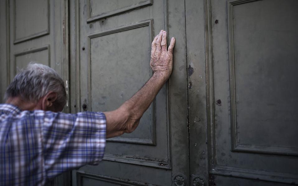 Görög nyugdíjas támasztja lemondóan a görög Nemzeti Bank ajtaját. (f.: Reuters)