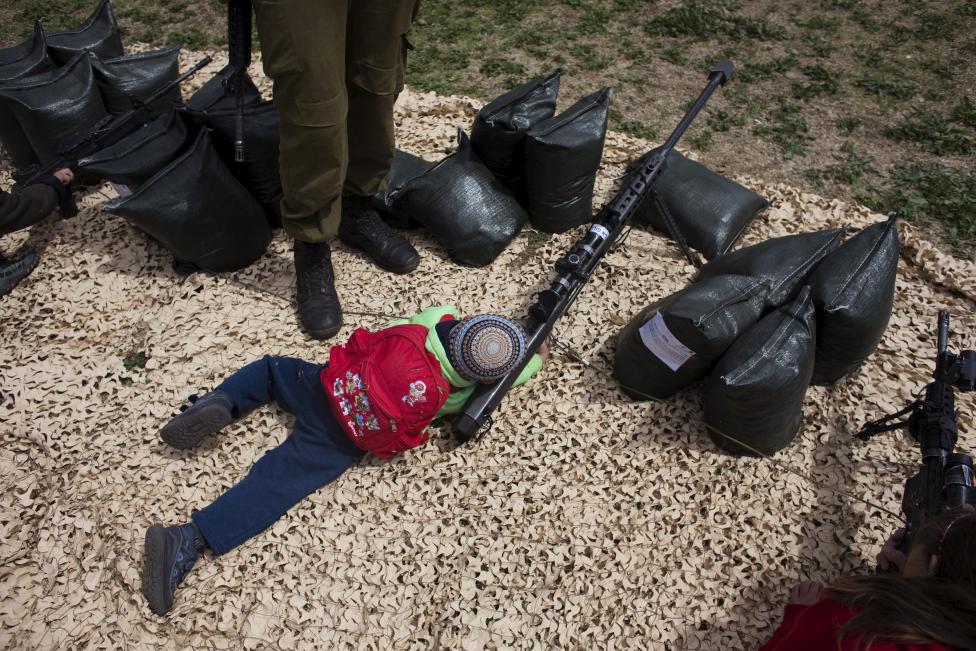 Egy fiatal fiú néz keresztül egy fegyver távcsövén az Izraeli Védelmi Erők által Ciszjordániában szervezett rendezvényen és kiállításon, ahol az izraeli hadsereg erejét és képességeit mutatták be. (f.: Reuters)