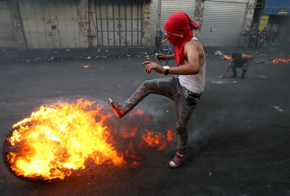 Palesztin férfi rúg arrébb egy lángoló gumiabroncsot Kelet-Jeruzsálem környékén. A Hamász vezetője a történteket a harmadik intifáda (népfelkelés) kezdetének nevezte. (f.: Reuters)