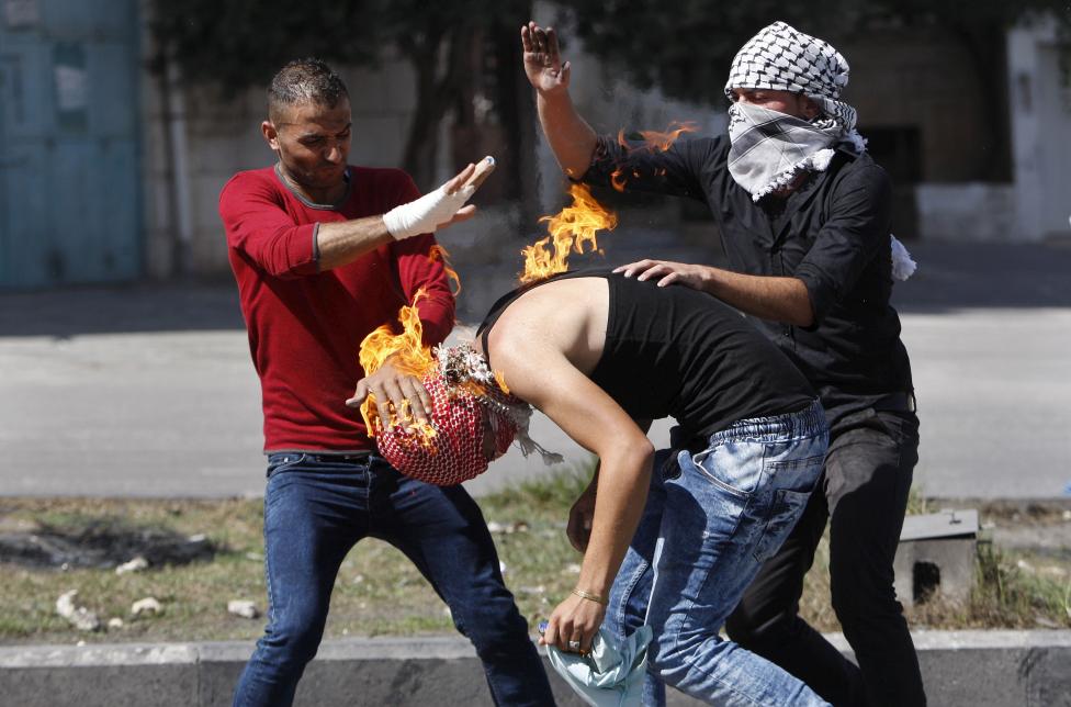 Palesztin tüntetők próbálják eloltani a lángokat egyik társukon, miután az sikertelenül próbált molotov koktélt dobni az izraeli katonákra. Kelet-Jeruzsálemben továbbra is feszült a biztonsági helyzet, több merénylet is történt az elmúlt napban. (f.: Reuters)