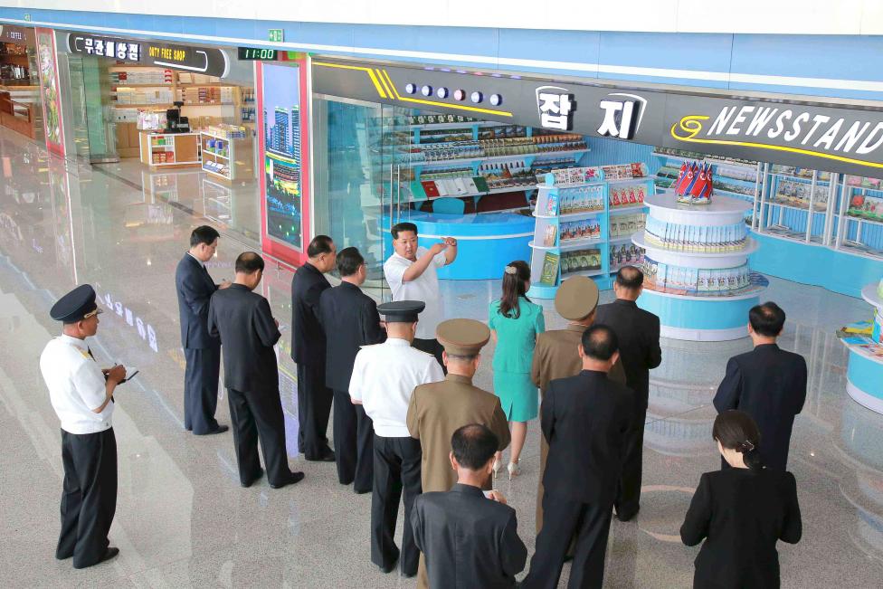 Kim Dzsong Un észak-koreai diktátor tart feleségével, Ri Sol Ju-val (mellette zöldeskék ruhában) bemutatót Phenjan új ‘nemzetközi‘ repülőterén. (f.: Észak-Koreai Sajtóügynökség)