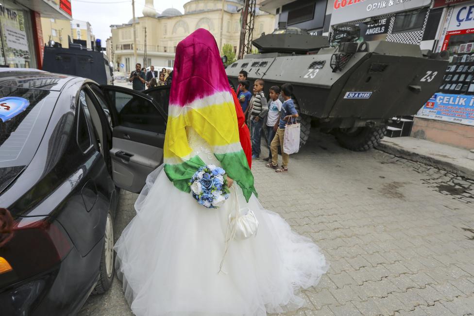 Kurd nemzeti színekbe borított menyasszony száll be az autóba, miközben az utcán páncélozott katonai járművek állomásoznak. A kurd milicisták és a török rendfenntartó erők július óta szinte naponta összecsapnak az ország délkeleti régiójában, miután összeomlott a Kurd Nemzeti Párt és és a török kormány közti 2 éves tűzszüneti időszak. (f.: Reuters) 