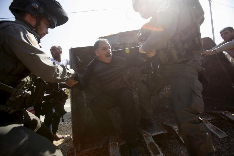 Izraeli határőrök próbálnak elvonszolni egy palesztin férfit a buldózer elöl, miközben az izraeli fegyveres erők farmokat dózerolnak le a Gázai-övezetben lévő Hebronnál. A palesztin lakókat arról értesítették, hogy nem rendelkeznek a szükséges lakhatási és területbirtoklási engedélyekkel. (f.: AFP)