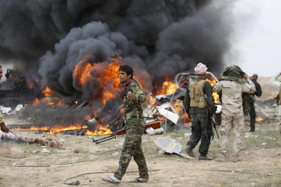 Síita milicisták állnak egy az Iszlám Állam öngyilkos merénylői által vezetett és önmagukkal együtt felrobbantott jármű előtt az iraki Tikrit városánál. Az iraki hadsereg és a milicisták a héten visszafoglalták a várost, stratégiai vereséget mérve a radikális iszlamista csoportra. (f.: Reuters)