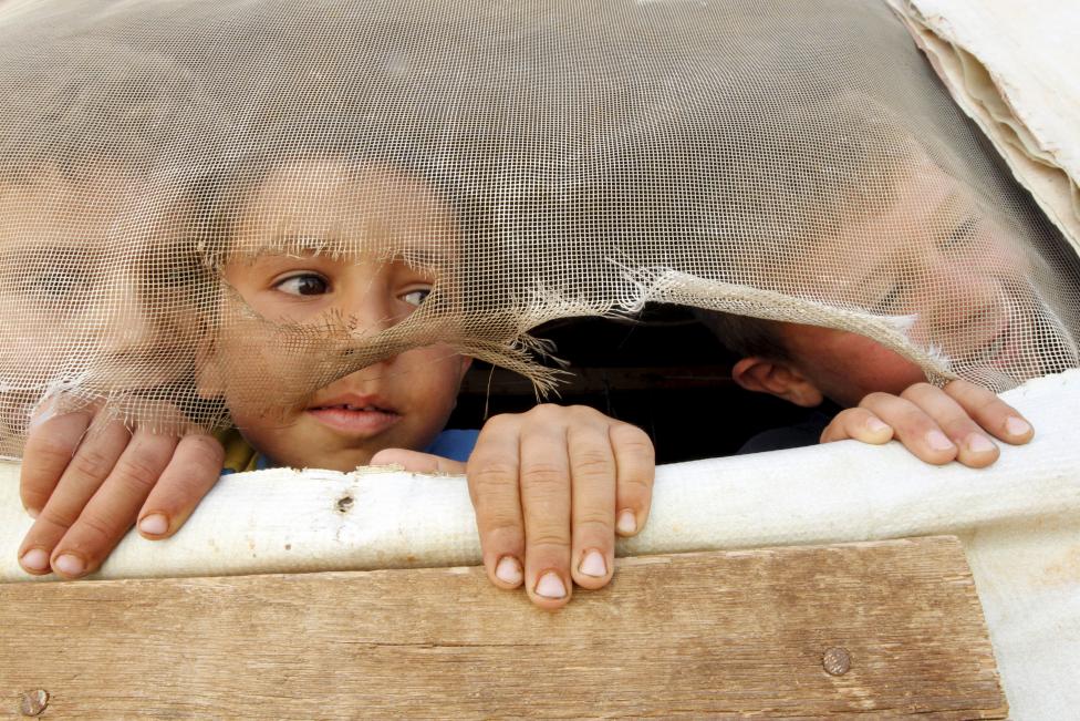 Szír menekült gyerekek tekintenek ki ideiglenesen épített lakósátraikból a libanoni Bekaa-völgyben lévő menekülttáborban. (f.: Reuters)