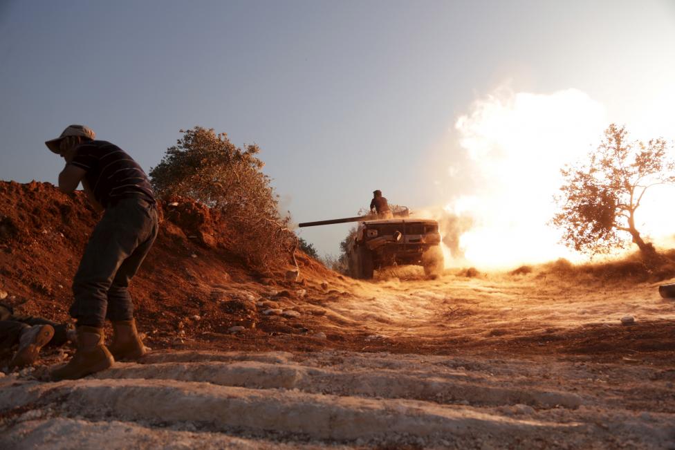 Szíriai lázadó fogja be a fülét, miközben társa lövéseket indít a közeli al-Mastouma katonai bázis ellen, Idlib közelében. (f.: Reuters)