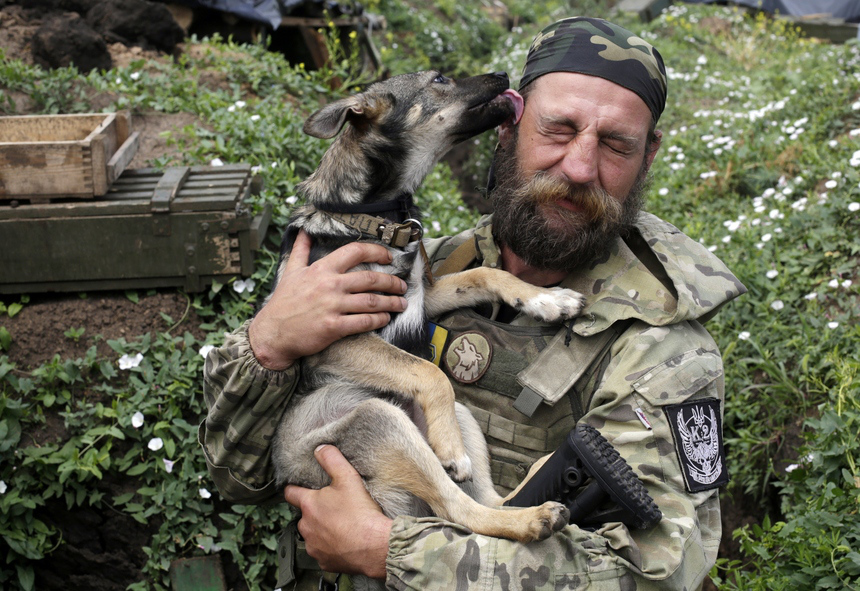 Ukrán katona ölel magához egy kutyát a kelet-ukrajnai frontvonalon. (f.: Reuters)