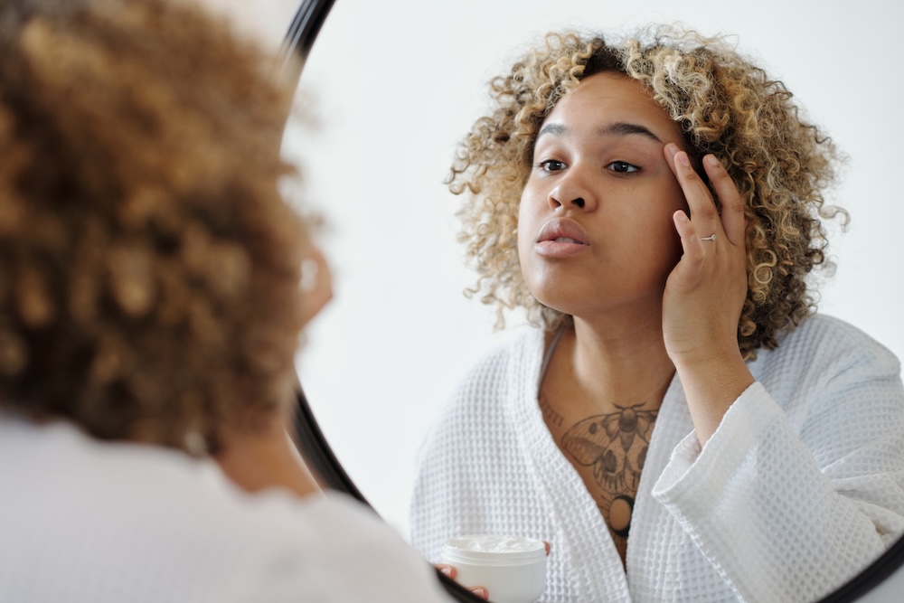 young-african-american-woman-applying-lotion-on-sk-2023-11-27-05-15-35-utc.jpg