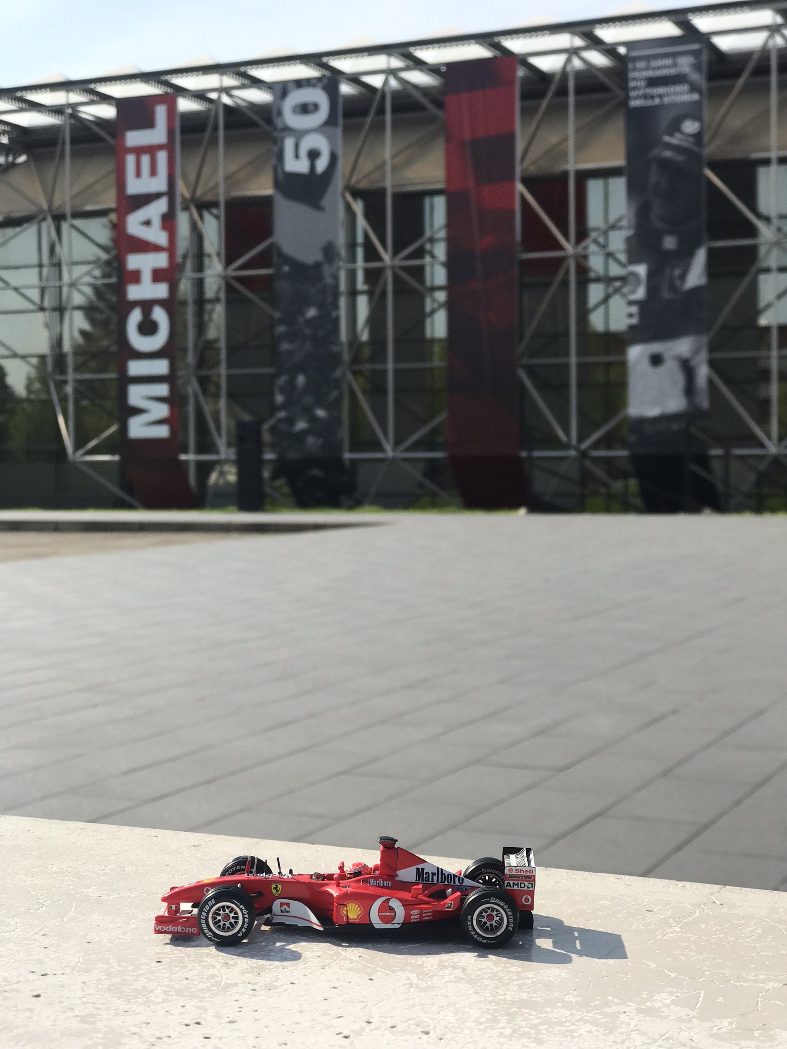 Schumacher kiállítást hirdető plakátok előtt immár Maranelloban