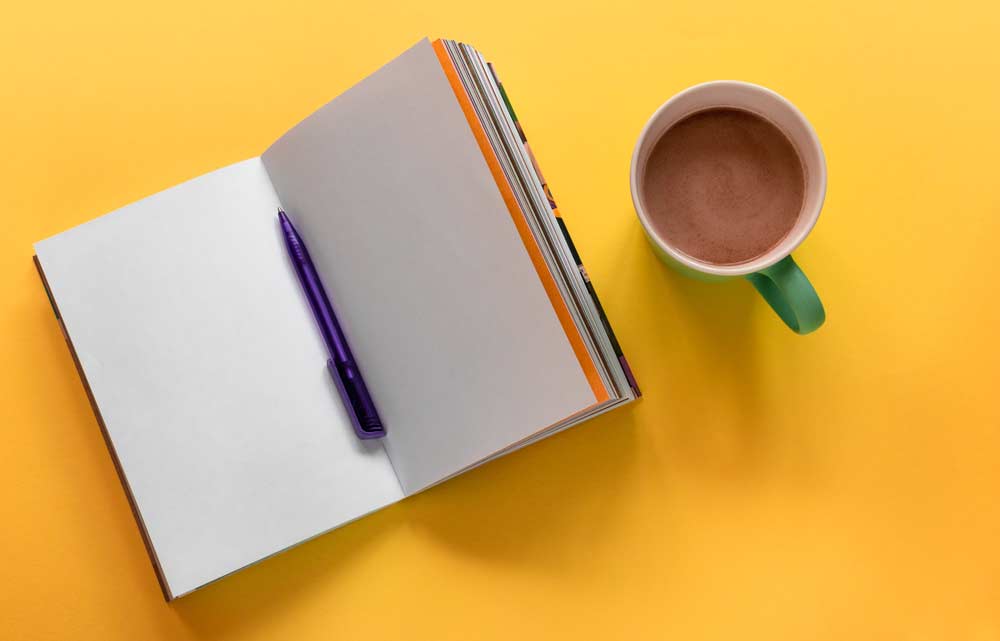 open-notebook-with-pen-and-cup.jpg