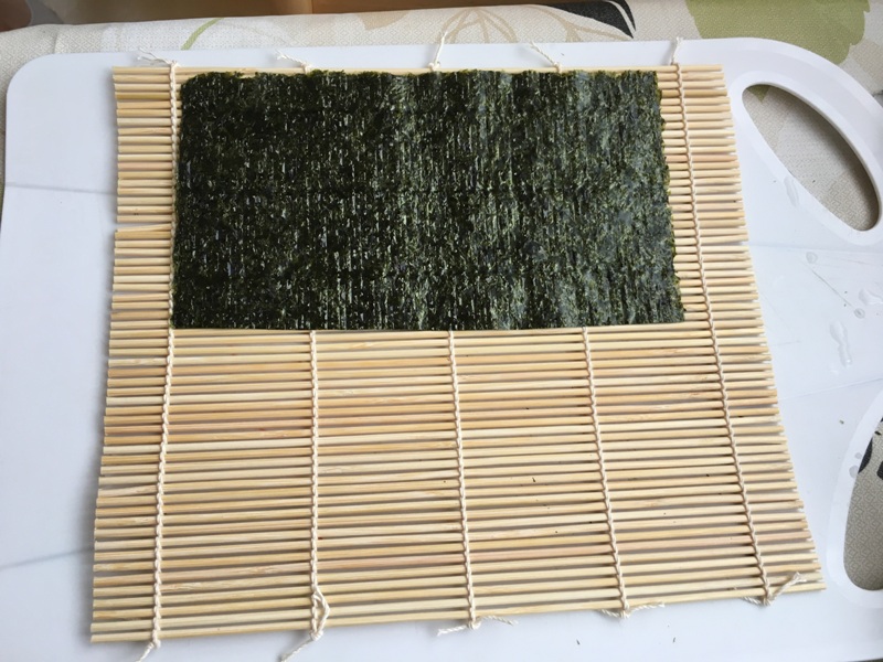 a bambusz feltekerő szélére helyezzük a nori (alga) lapot <br />place nori (seewheed) on a bamboo sheet